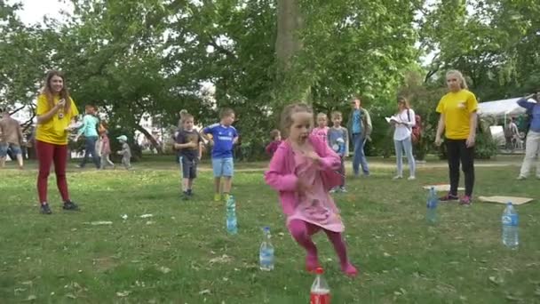 Los niños corren, corren, se doblan alrededor de botellas saltando trozos de papel — Vídeos de Stock