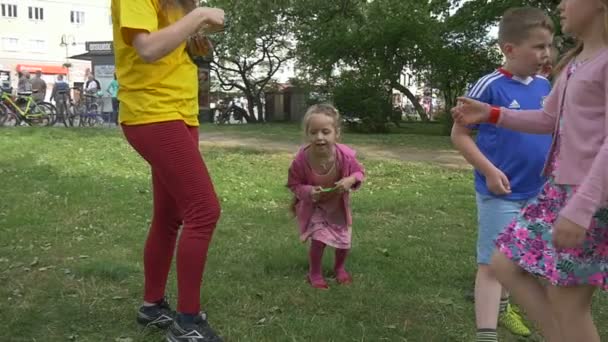 Los niños corren, corren, se doblan alrededor de botellas saltando trozos de papel — Vídeos de Stock