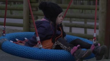 Çocuk Bir Yuva Salıncak üzerinde oturuyor ve Swaying Daughter Bir Parkta Çocuk bir Salıncak üzerinde oynuyor ve Baba Aile Bir Oyun Alanı üzerinde bir dinlenme var gülüyor