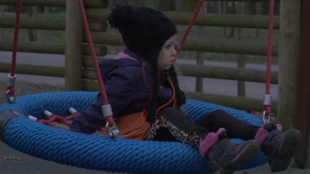Kid sitter på ett bo swing och vajande dotter spelar på en gunga i en Park barn och pappa skrattar familj har en vila på en lekplats — Stockvideo