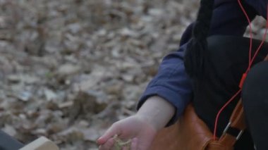 Çocuk masa sandalye üzerinde oturan ve sallayarak kumdan siyah şapka ve Brown Bag ile eller çocukta Resting Park sonbahar akşam zaman bulutlu içinde olduğunu