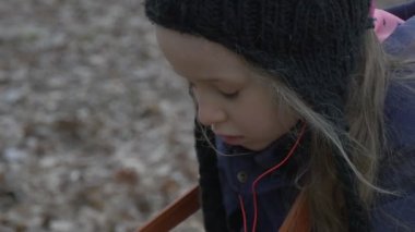 Sarışın kız oturuyor bir Resepsiyon sandalye sarsma siyah şapka ve Brown Bag ile eller çocukta tozlar üzerinde Resting Park sonbahar akşam zaman bulutlu içinde olduğunu