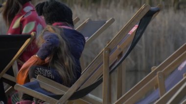 Kız sandalyede oturan ve Rummages çanta insanlar vardır oturma etrafında Her sarışın çocuk dinlenme Pier akşam zaman güneşli gün Opole Polonya açık havada Tarih içinde