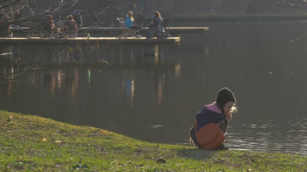 Людей у шезлонгах дитина дивиться в Грін Бенк води озера ходьба поблизу спокійний безтурботний ставок "брижі" зелений трава вечір сутінки Sunset весни — стокове відео