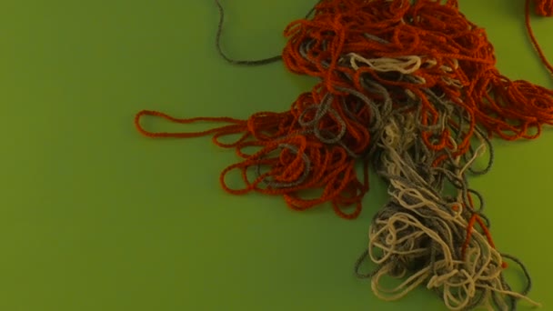 Quelqu'un tire un tas enchevêtré de fils de laine sur l'écran vert tas de fils colorés enchevêtrés sont en mouvement morceaux coupés de fils enlevés 