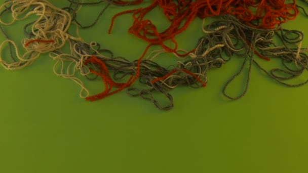 Quelqu'un tire un fil de trois couleurs fils de laine sur l'écran vert tas de fils colorés enchevêtrés se déplacent morceaux coupés de fils enlevés 