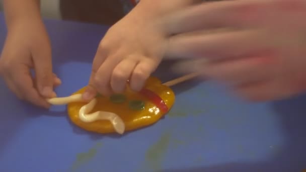 Kid está consertando uma decoração de caramelo para doces aprendendo a fazer doces de caramelo circular amarelo em um confeiteiro de vara está ensinando as crianças como fazê-lo — Vídeo de Stock