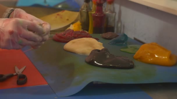 Les enfants apprennent à fabriquer des bonbons coupés en morceaux Fixer un décor à un caramel sur un bâton Confectionneur enseigne aux enfants Excursion dans une usine de bonbons — Video