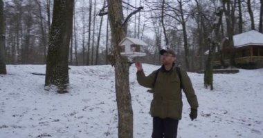 Ağaç adam gelir ve besleyici Park zemine görünüyor kar çıplak ağaçlar gri gökyüzü bulutlu kış günü Kiev Ukrayna ile kaplı