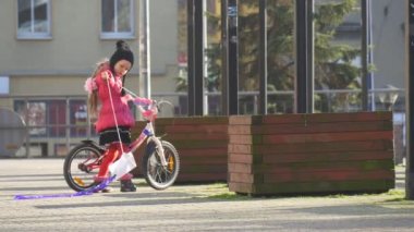 Çocuk kızı oturur ve binicilik bisiklet uçurtma bir bisiklet dümen küçük kız başlar yolculuk Raising kız uçurtma bir kırmızı ceket güneşli gün ilkbaharda sabit