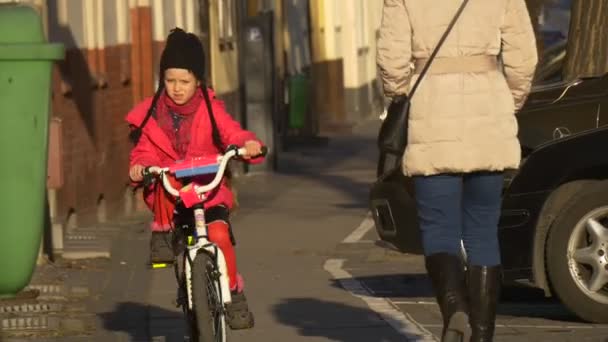 A menina está andando de bicicleta para cima pela City Street Opole Poland City Day A criança está andando entre as pessoas andando por uma rua vintage Sunny Day Spring — Vídeo de Stock