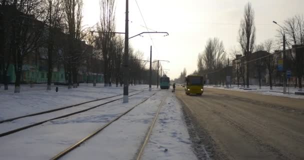 Tram op het station Auto's en gele bus verhuizen naar camera residental huizen langs een straat oude tram op Mir Avenue in Konotop stad Oekraïne winter — Stockvideo