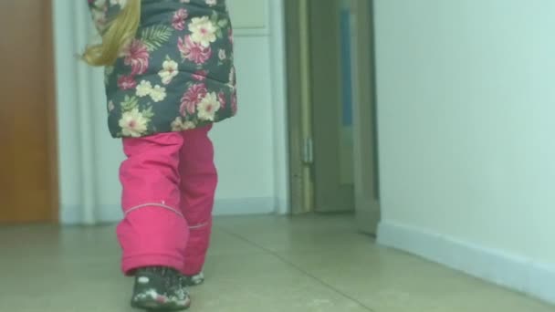 Bambina con lunga treccia sta camminando Home Entra nell'edificio in inverno Slow Motion Snow on a Boots Ragazza gelida in giacca a fiori e pantaloni rosa — Video Stock