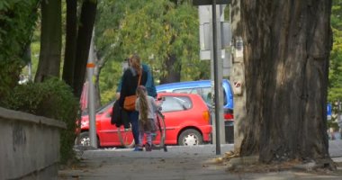 Anne ve Küçük Blonde Girl Kick Scooter Anne ve Kızı Sokak Ağaçları Bisiklet Alley Tree Trunks Cars tarafından Street Man tarafından Yürüyüş