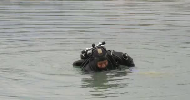 Twee mannen duikers in zwemkleding staan in het water praten het houden van de flippers eindigde de duiken wandelen uit water cirkels op waterige oppervlakte — Stockvideo
