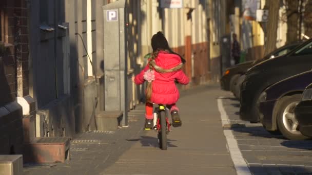 Ragazza sta cavalcando la bicicletta giù da City Street Opole Poland City Day Bambino sta cavalcando tra la gente che cammina da una strada Sunny Day Spring Time — Video Stock