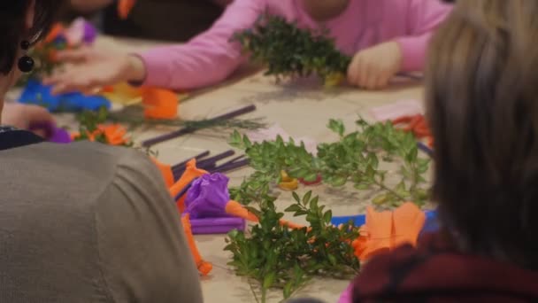 Lidé dělají papírové květiny kytice výdeje zelené větve rodiny Master třídy Opole Polsko příprava na velikonoční oslavu barevné vejce na stůl — Stock video