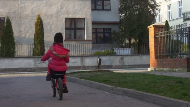 Niña está montando la bicicleta alrededor de la cerca de la esquina de un edificio Opole Polonia Niño está montando lejos por una calle Aprendiendo a cabalgar soleado Día Primavera — Vídeos de Stock