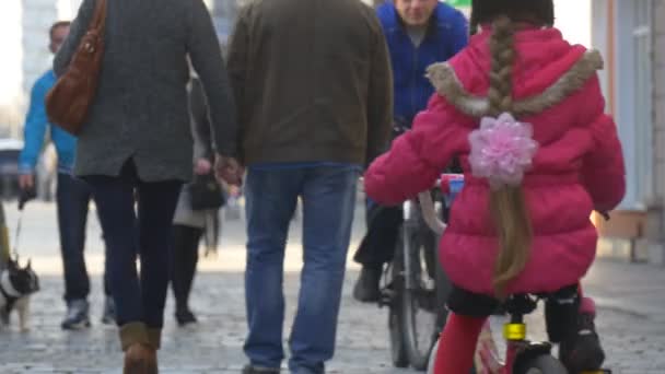 Klein meisje op de fiets op het stadsplein in Opole Polen stad dag mensen lopen met kleine honden staande praten menigte van mensen in zonnige dag Springtime — Stockvideo