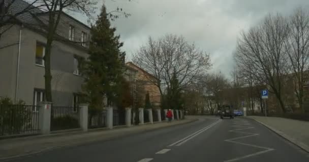 Kahle Äste Bäume entlang einer Straße Auto mit Kamera im Inneren bewegt sich durch die Stadt Straße entlang einer alten Gebäude Zaun andere Autos auf der Straße bewölkten Tag — Stockvideo