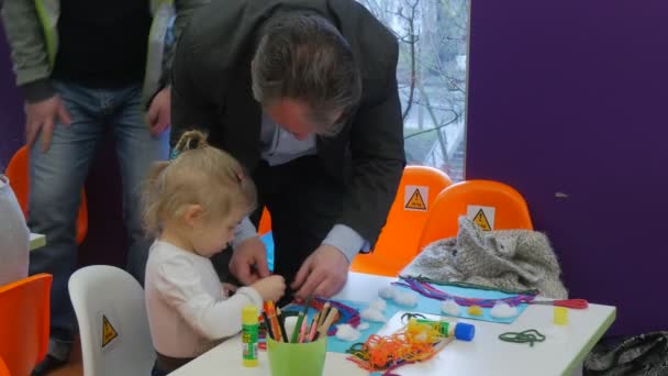 Pappa och liten flicka barnens dag i biblioteket Opole Polen far hjälper ungen att göra en regnbåge Applique målning föräldrar tillbringa tid med sina barn — Stockvideo