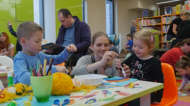 Leraar speelt met Kid Children's dag in bibliotheek Opole Polen moeder pedagoog helpt het kind om een garen stoffen lijm ouders tijd doorbrengen met hun kinderen — Stockvideo