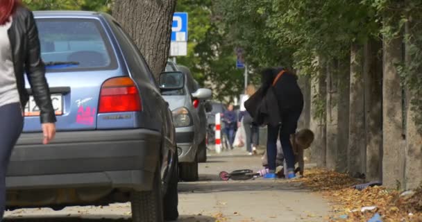 Anne ve Küçük Blonde Girl Kid Onun Kick Scooter Kırmızı Araba Street Kick Scooter De İnsanlar Arrives Lider Sürme Anne kadar kaldırmaya yardımcı olur Falled has — Stok video