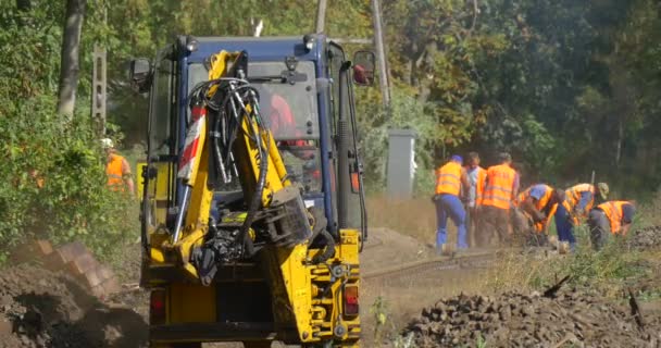 Des travailleurs travaillent creusent une excavatrice jaune creuse un bâtiment sur la route forestière Grove sur le fond Des voitures passent par la route — Video