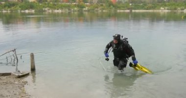 Mayo man Dalgıç Tutarak Flippers Bir Horizon Üzerinde Karşı Banka River Bank Beach Binalar a River Bank Beach Binalar a Dalış Out Of Water Yürüyüş Bitirdi