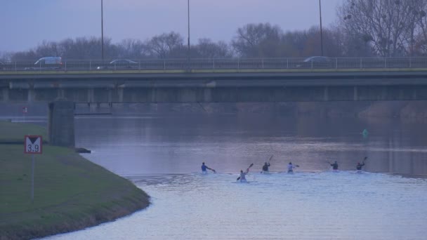 Mężczyzn kajaki kajaki pod most wysokość limitu znak miasto na brzegu rzeki Glide całej rzeki Green Park w pobliżu mostu samochodu wody poprzez Zmierzch River — Wideo stockowe