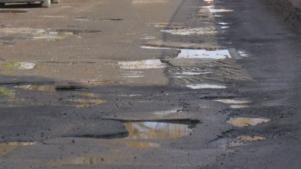 Pölar på en Road vatten i gropar bil är parkerade våt asfalt efter regn Sky reflektion i en vatten City Street solig dag på vintern eller våren utomhus — Stockvideo