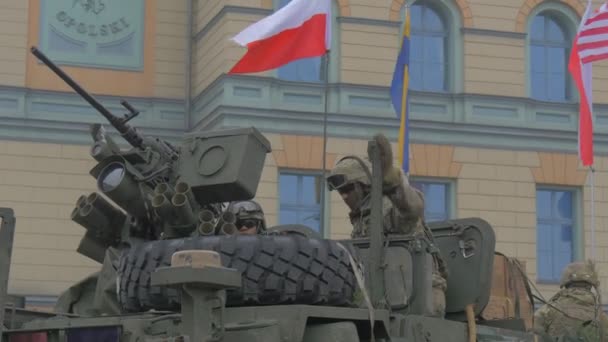 Soldado senta-se em uma cabine de tanque levantando-se olhando ao redor Lançador em uma torre polonês ucraniano us bandeiras estão acenando Nato formação multinacional na Polônia — Vídeo de Stock