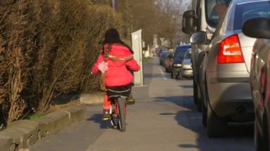 Küçük kız at binme Bisiklet beceriksizce şehir meydanında Opole Polonya şehir gün çocuk sürme arasında insanlar tarafından bir cadde Sunny gün bahar yürüyor