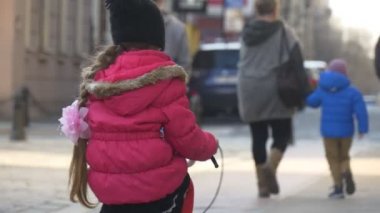 Küçük kız sürme Şehir Meydanı durak teslim Opole Polonya çocuk bisikletle sürme arasında kalabalık, insanlar aileler tarafından bir Street güneşli gün ilkbaharda olduğunu.