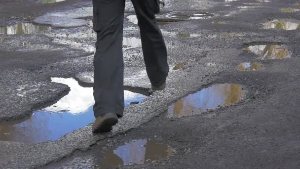 Backpacker in Red is Jumping Through Puddles Running by Wet Road Feet Close up Wet Asphalt After Rain Sky Reflection in a Water Sunny Day in Winter Spring — Stock Video