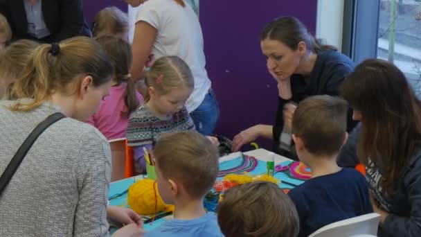 Dzieci pedagogów w dzień dziecka w bibliotece Opole Polska dzieci są malarstwo Making Applique Rainbow kolorowych wątków obracając głowy uśmiechnięty — Wideo stockowe