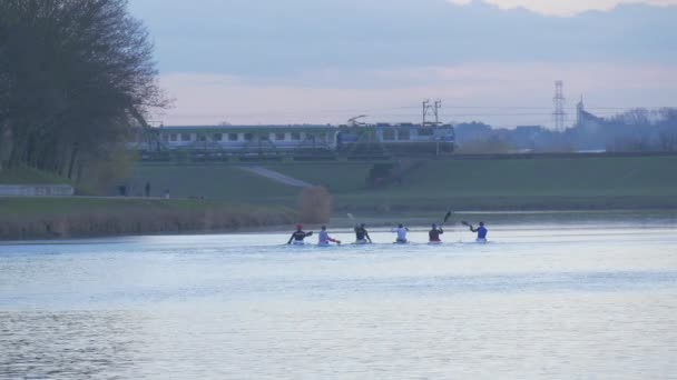 Los deportistas están navegando en kayak El tren es conducido por Bridge Paddle a Canoas Deslízate a través del Parque Verde del Río Cerca del Puente del Ferrocarril Acuático A través del Día Nublado — Vídeos de Stock