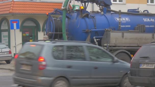 Trabajadores Blue Tank Opole City Day Sewer Limpieza Stormwater Runoff Limpieza Flasher se fija en un camión Coches son conducidos Mujer está cruzando la carretera Paisaje urbano — Vídeo de stock