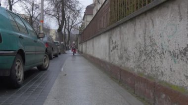 Çocuk bir bisiklet sürme Hill Şehir sokak arabalar vardır park boyunca bir kaldırım yol işaretleri Cityscape küçük çiçekli ceket oynarken açık havada kızıdır