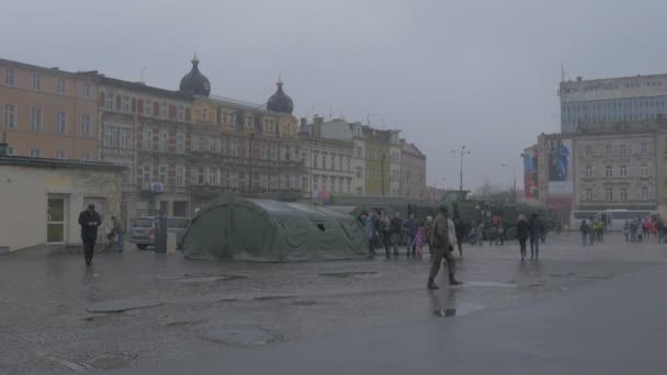 Άνθρωποι κοντά σε κατασκήνωση του ΝΑΤΟ υπερατλαντικός επίλυση επιχειρήσεων στρατιώτες σε μια πόλη πλατεία στρατιωτικού εξοπλισμού ειρηνευτική εκπαίδευση οικογένειες παιδιά αναζητούν — Αρχείο Βίντεο