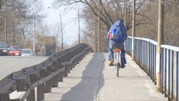 Człowiek jedzie na chodniku wzdłuż samochodów drogowych jazdy na autostradzie na Automobile Bridge ogrodzenia bezpieczeństwa na boki drogi w ciągu dnia na zewnątrz — Wideo stockowe