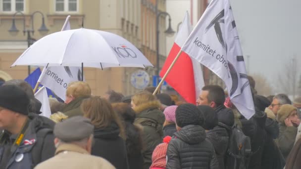 Treffen des Komitees zur Verteidigung der Demokratie in Polen: Menschen halten Plakate mit dem Regenschirm des Komitees und schwenken polnische Fahnen auf dem Stadtplatz — Stockvideo