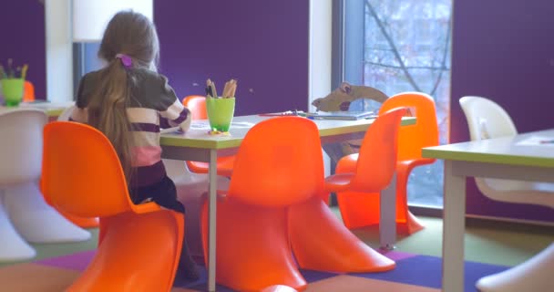Dívka sedí zpět do komory na židli. — Stock video