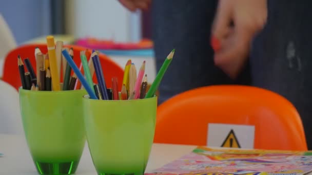 Professora desfocada pega um lápis Copos verdes com lápis estão na mesa Sala de aula na Biblioteca Central Opole Polônia Pais passam tempo com crianças — Vídeo de Stock