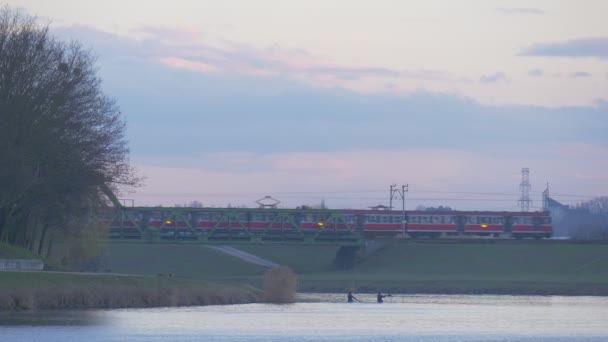 Twee mannen zijn kajakken lopen mensen trein mensen Paddle kano's glijden over de rivier groen Park in de buurt van de spoorwegbrug Water door rivier Dusk — Stockvideo