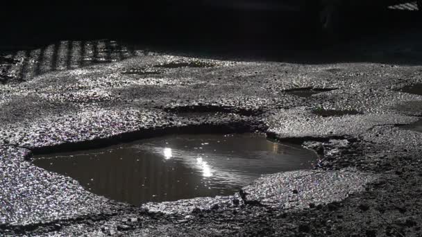 湿式道路水たまり太陽輝く水ピット車の車輪晴れた日太陽反射、水濡れたアスファルト未修理道路屋外での走行します。 — ストック動画