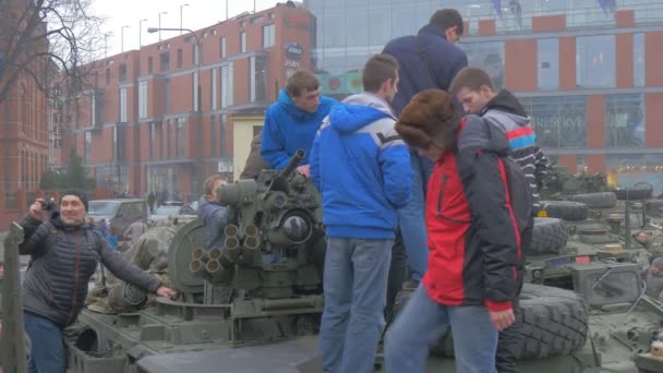 Adolescentes em excursão de tanque ao acampamento militar Soldados da OTAN em camuflagem mostram um tanque para um povo Outros estão olhando para veículos militares Praça da Cidade — Vídeo de Stock