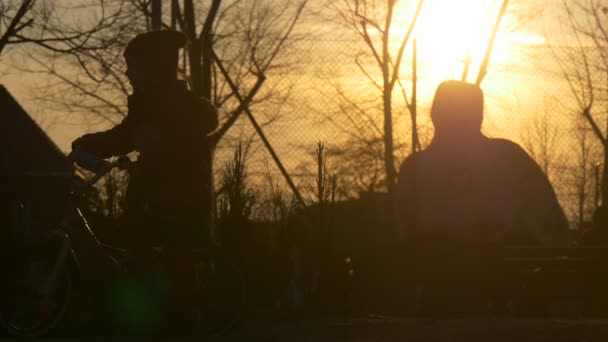 Silhouette de petite fille tenant un vélo à vélo près de Park City Street dans la soirée Coucher de soleil Silhouette au soleil Pavage Pierres Personnes Silhouettes — Video