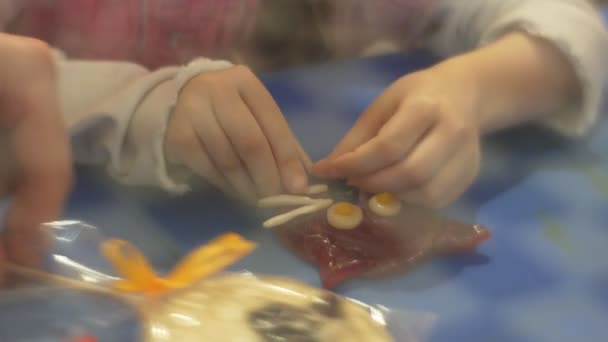 Kid is Decorating a Cat Shaped Candy Mustaches Learning to Make Sweets Excursion to Sweets Factory Caramel on a Stick Confectioner is Teaching the Kid — Stock Video