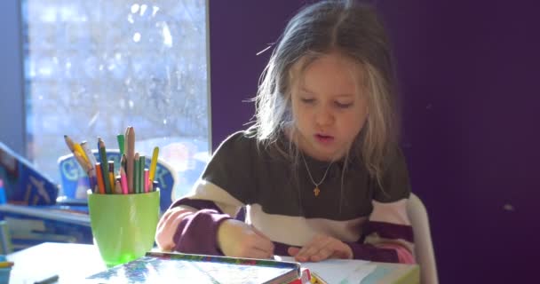 A menina de cabelos justos sentada em um quarto violeta perto de uma janela — Vídeo de Stock